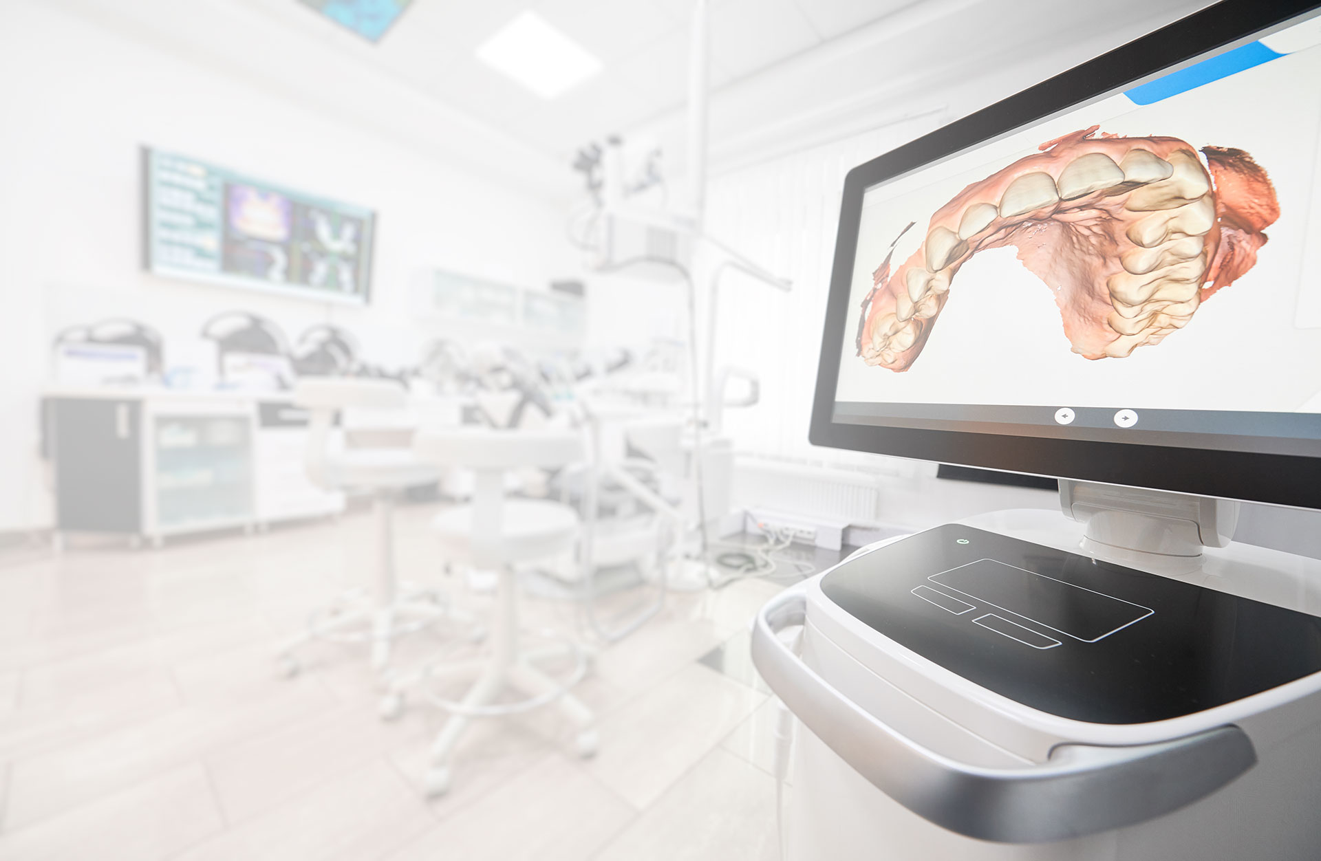 Anatomical model of a human mouth displayed on a computer screen inside a dental office setting.