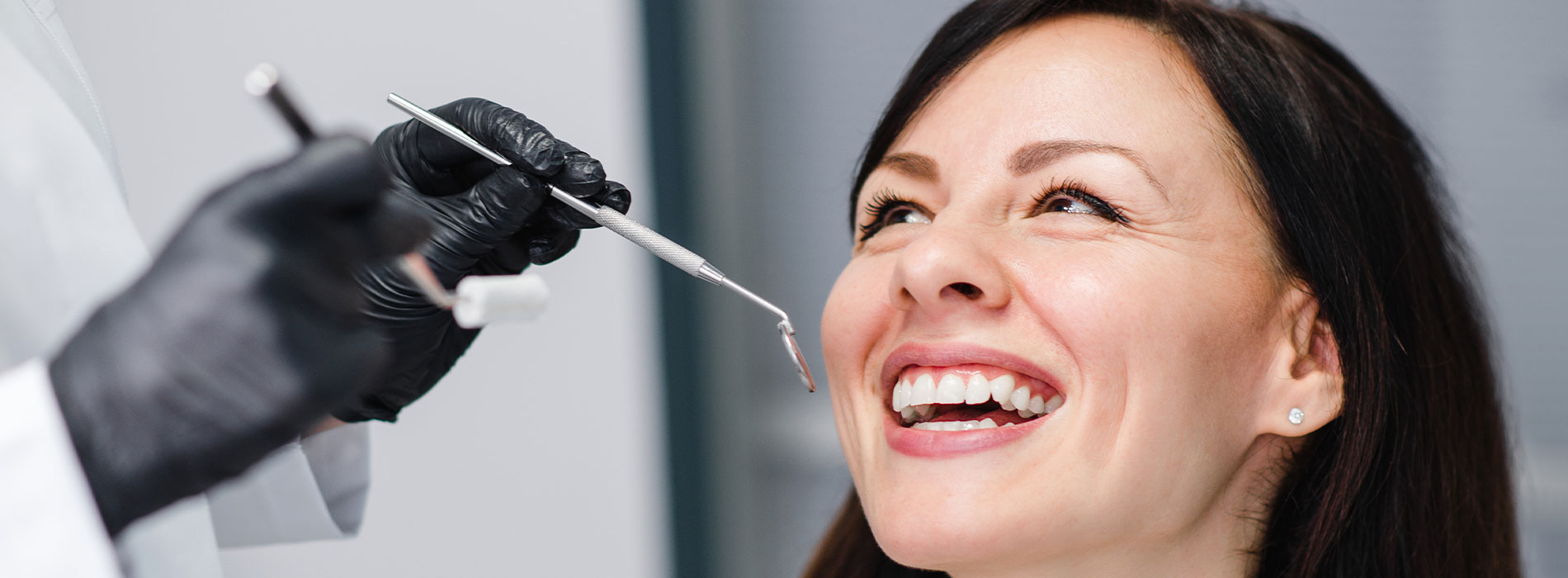 A woman receiving dental treatment with a smiling expression, surrounded by dental equipment and personnel.