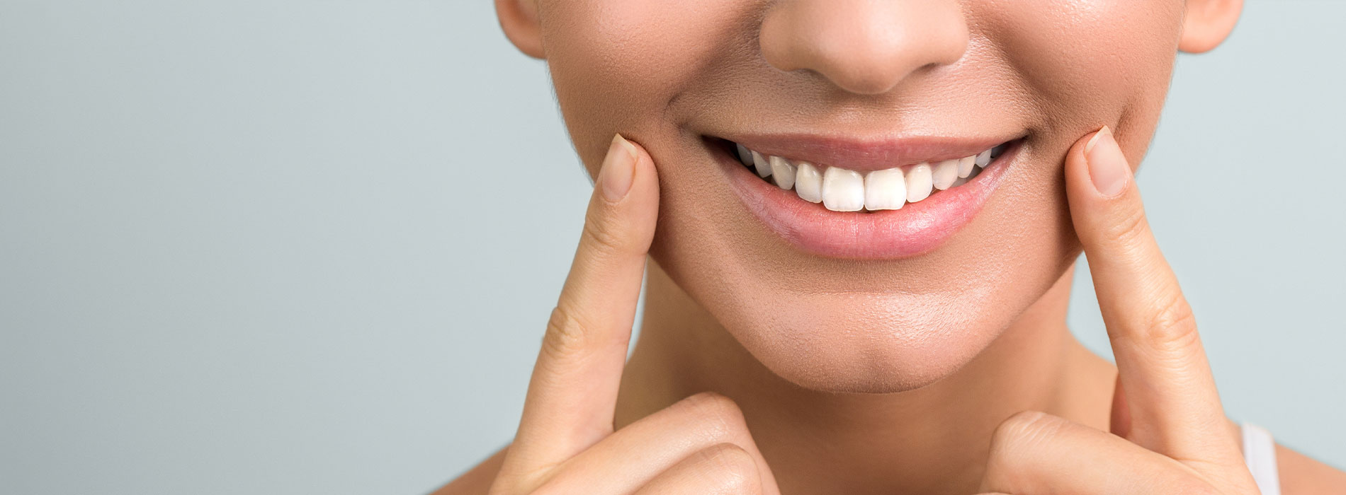 A person smiling while holding their cheeks with both hands.