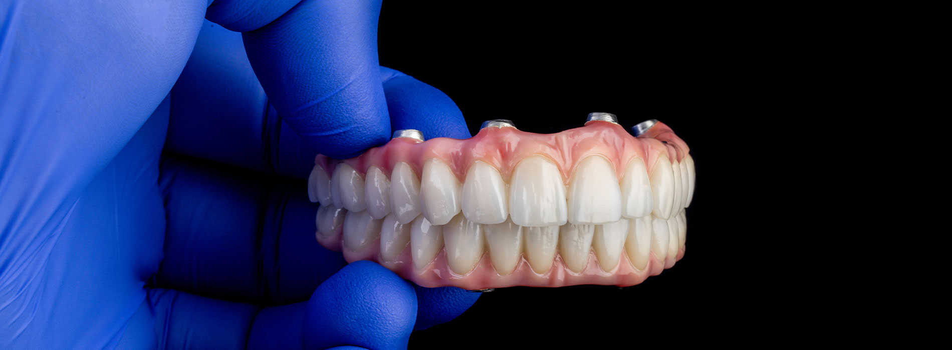 The image shows a pair of human teeth being prepared by dental tools under a magnifying glass, with a blue background and a focus on the precision of dental work.