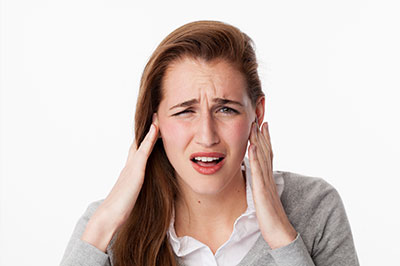 The image shows a young woman with her hand on her head, appearing distressed or overwhelmed, against a plain background.