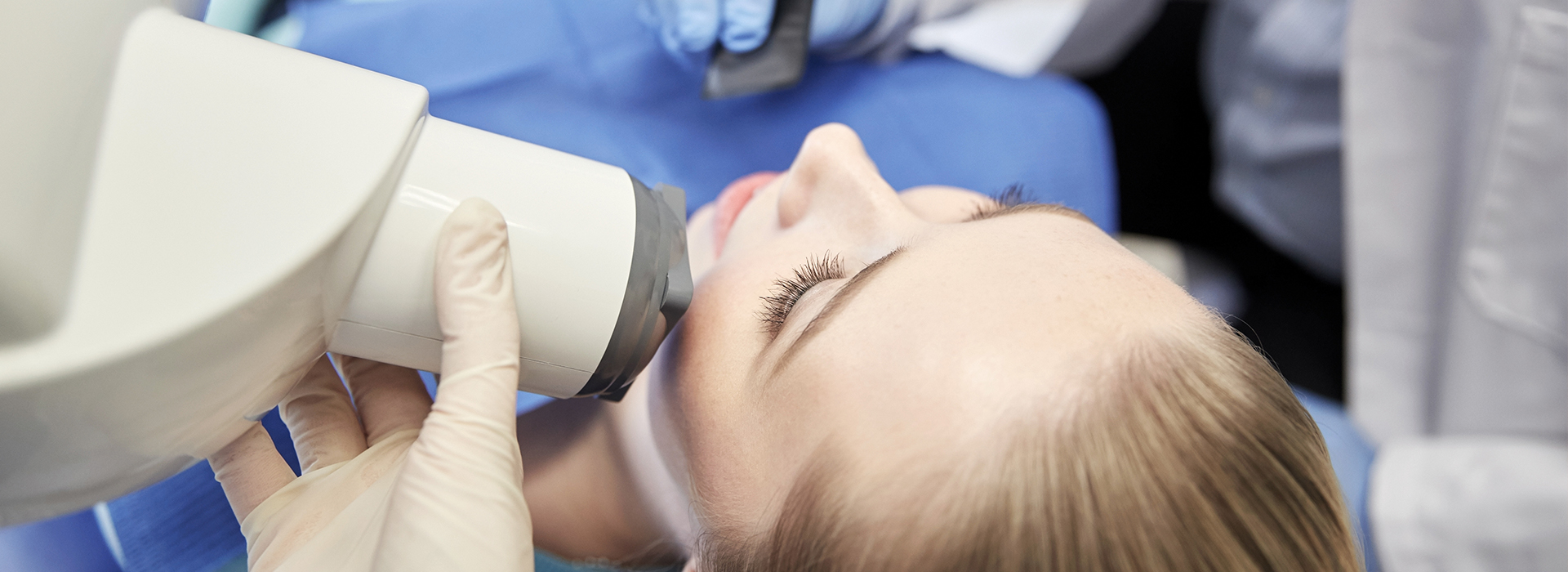 An individual receiving a medical procedure with a device attached to their face, likely for cosmetic or medical purposes, under observation by a healthcare professional.
