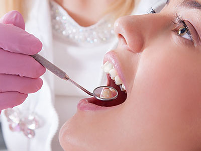 A person receiving dental treatment with a dentist using a drill on their teeth.