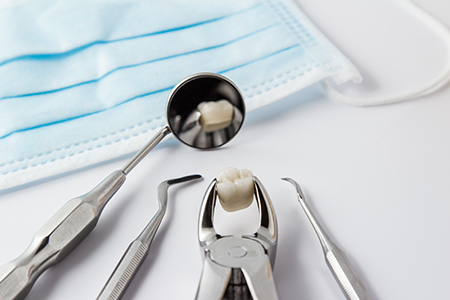 The image shows a dental tool with a tooth inside it, resting on a blue surgical drape, which is placed on top of a white surface.