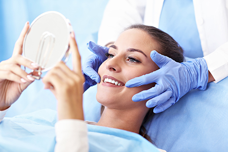 Woman in medical setting receiving facial treatment with magnifying mirror.