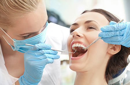 The image shows a dental professional performing oral care on a patient, with both individuals wearing protective gloves and masks.