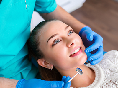 A woman receiving dental care from a professional, with the dental practitioner adjusting her mouthpiece.