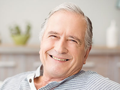 The image shows a smiling elderly man sitting comfortably with his eyes closed, appearing relaxed and content.